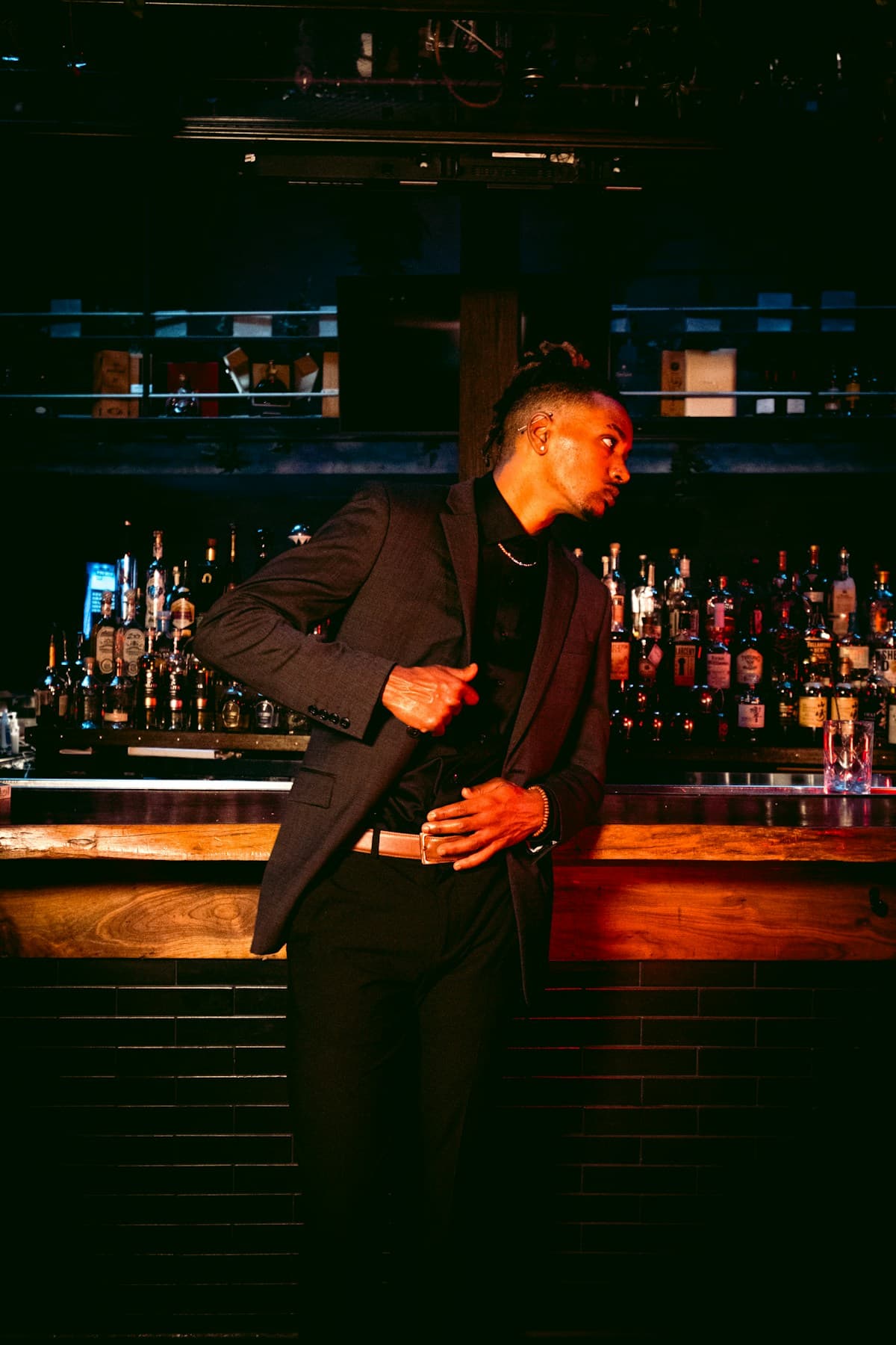 Man in suit leaning at a dark bar