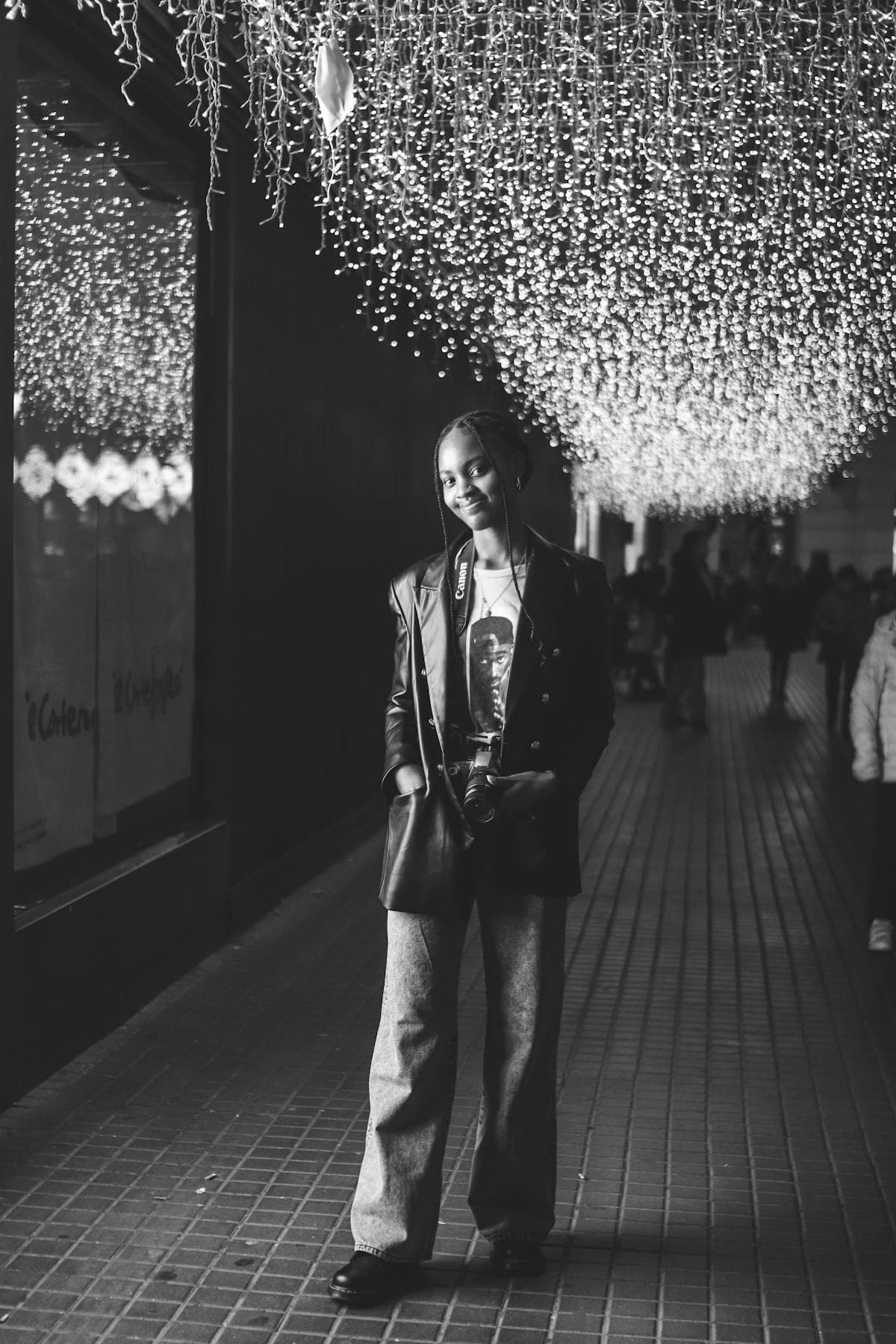 Woman with braids holding a camera under warm lights